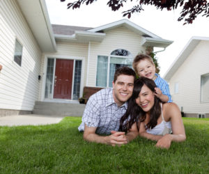 Portrait of happy family lying down on grass in front of house