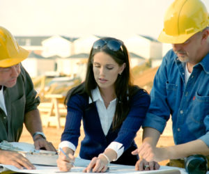 Construction workers look at and discuss plans.